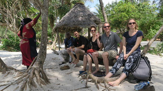 A group of young European people sits on a log