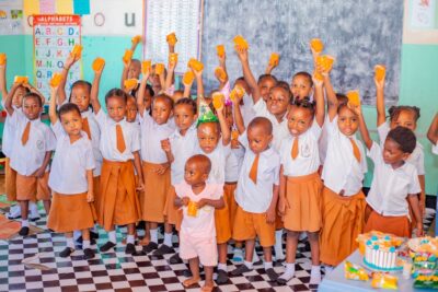 Photo of children in school uniforms smiling happily at the camera